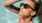 woman wearing sunglasses stands in a pool and basks in the sun