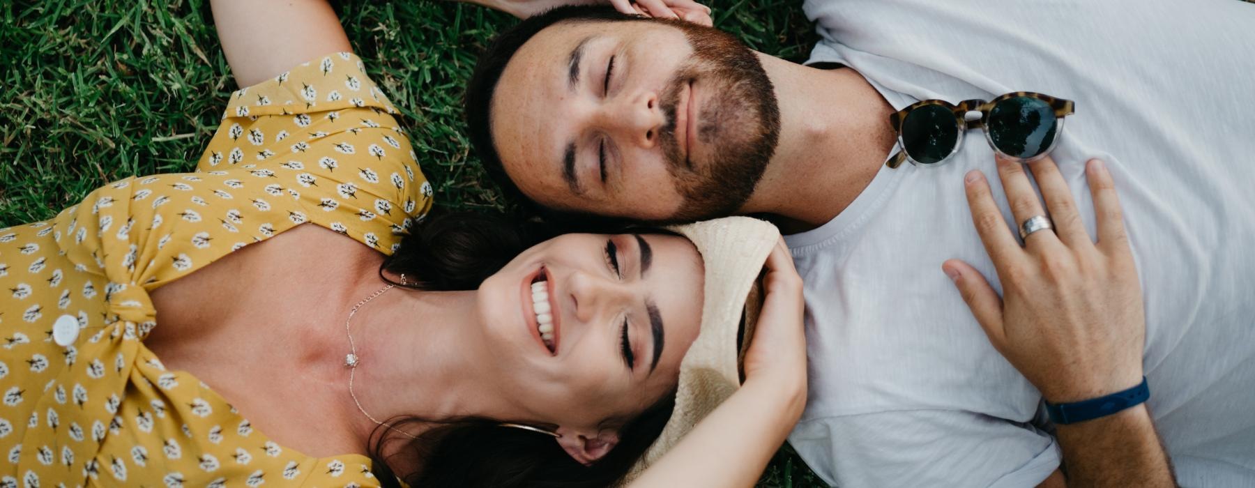 a man and woman lying in the grass